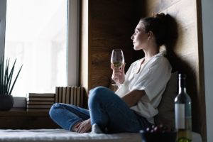 Woman drinking wine and pondering if she is over drinking