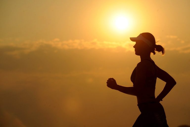 A woman running silhouetted by the sun