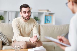 man on couch in yellow sweater discussing drug and alcohol detox