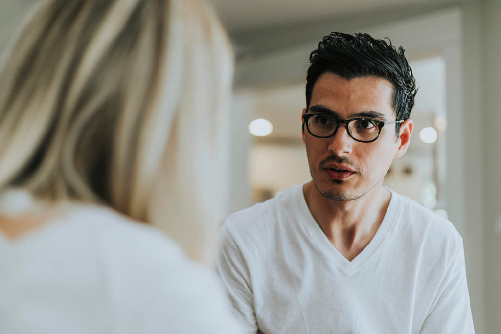 man in glasses talking to woman about mental health treatment