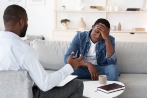 Man in chair in conversation with man on couch