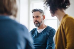 a man is moved listening to stories in group therapy for alcohol addiction treatment