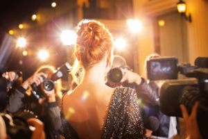 a famous celebrity is greeted by cameras on the red carpet