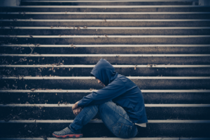 a man struggles with cocaine addiction withdrawals on the steps of a large building