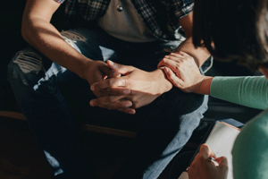 a therapist reaches out to touch the arm of and support a client in continuing care 