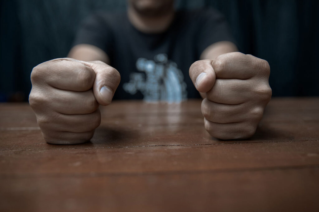 a man unable to manage his anger slams his fists on a table looking for anger management therapy