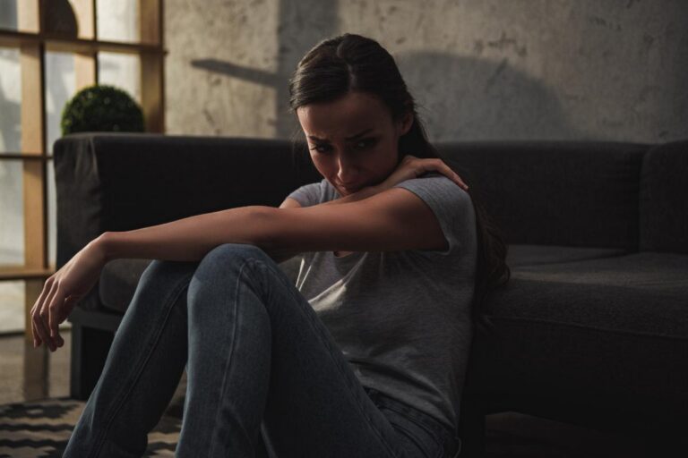 A young woman with morphine addiction sitting on floor looking distressed