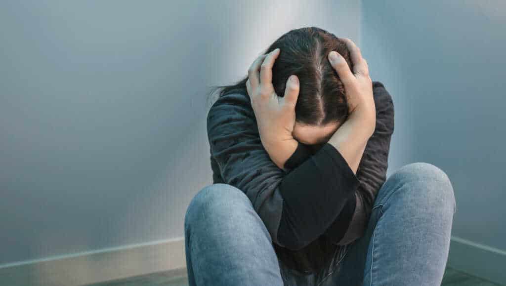 A person suffering from post acute withdrawal symptoms sitting on the floor