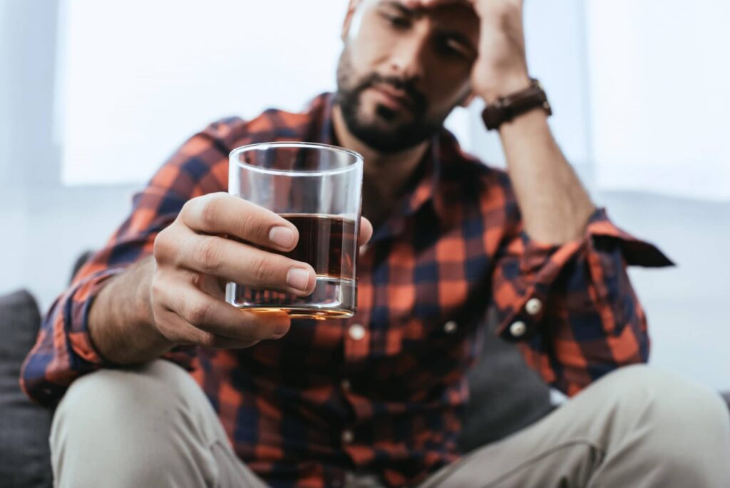 Man contemplates drinking another glass of liquor