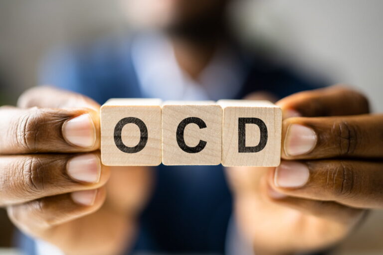 A person holding up blocks that spell OCD