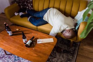 Man blacked out drunk, passed out on the couch surrounded by bottles