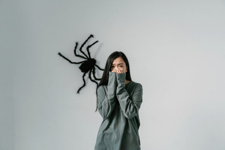 Woman with a phobia and a spider behind her