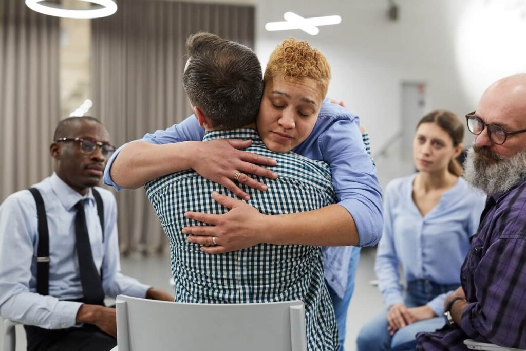 woman hugging a man during an alcohol rehab meeting