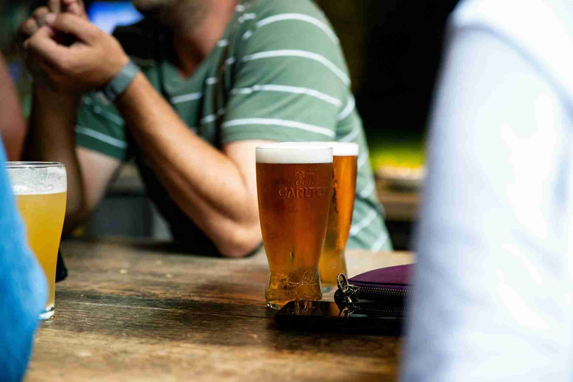 Glasses of beer on a table during a social gathering, representing social drinking and potential alcohol use disorder.