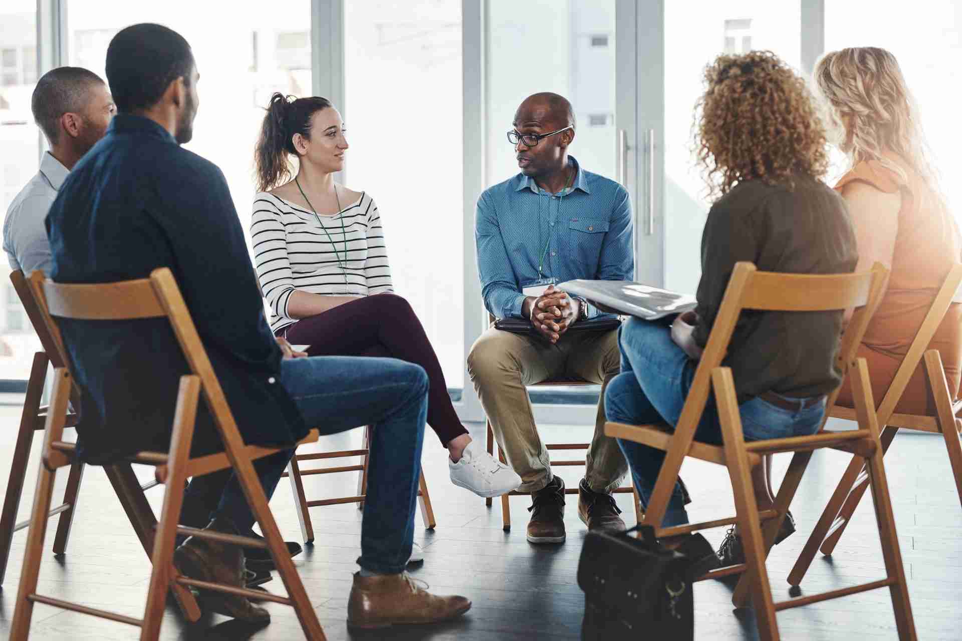 Group therapy session with a counselor and participants discussing addiction recovery and mental health treatment