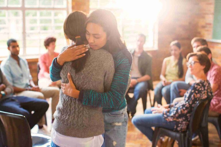 Two people embracing during a group therapy session for addiction recovery and emotional support
