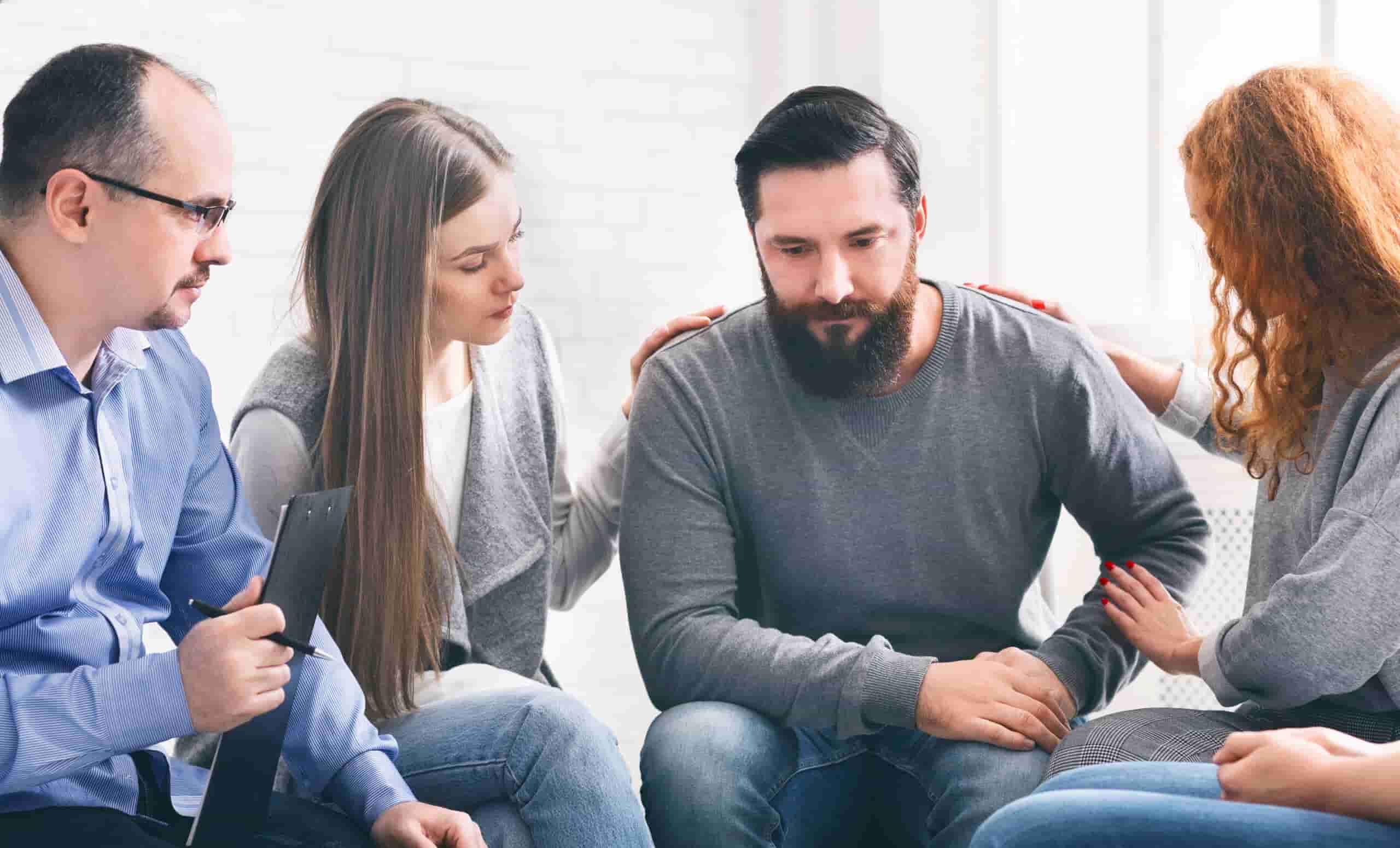 Therapist and support group encouraging a man during alcohol rehab in Georgia.