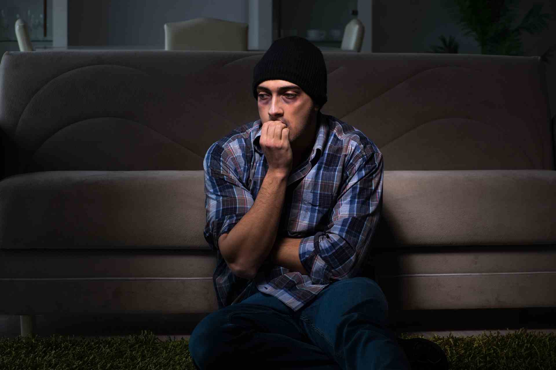 Man sitting on the floor looking anxious, representing benzodiazepine dependence, withdrawal, and addiction recovery.