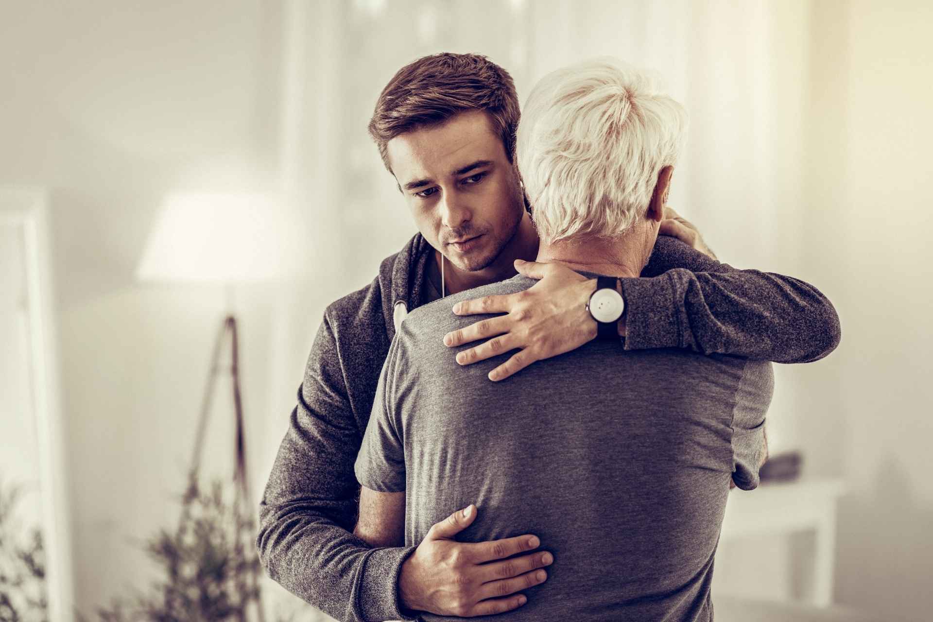 Young man comforting an older man while coping with alcohol-related health concerns