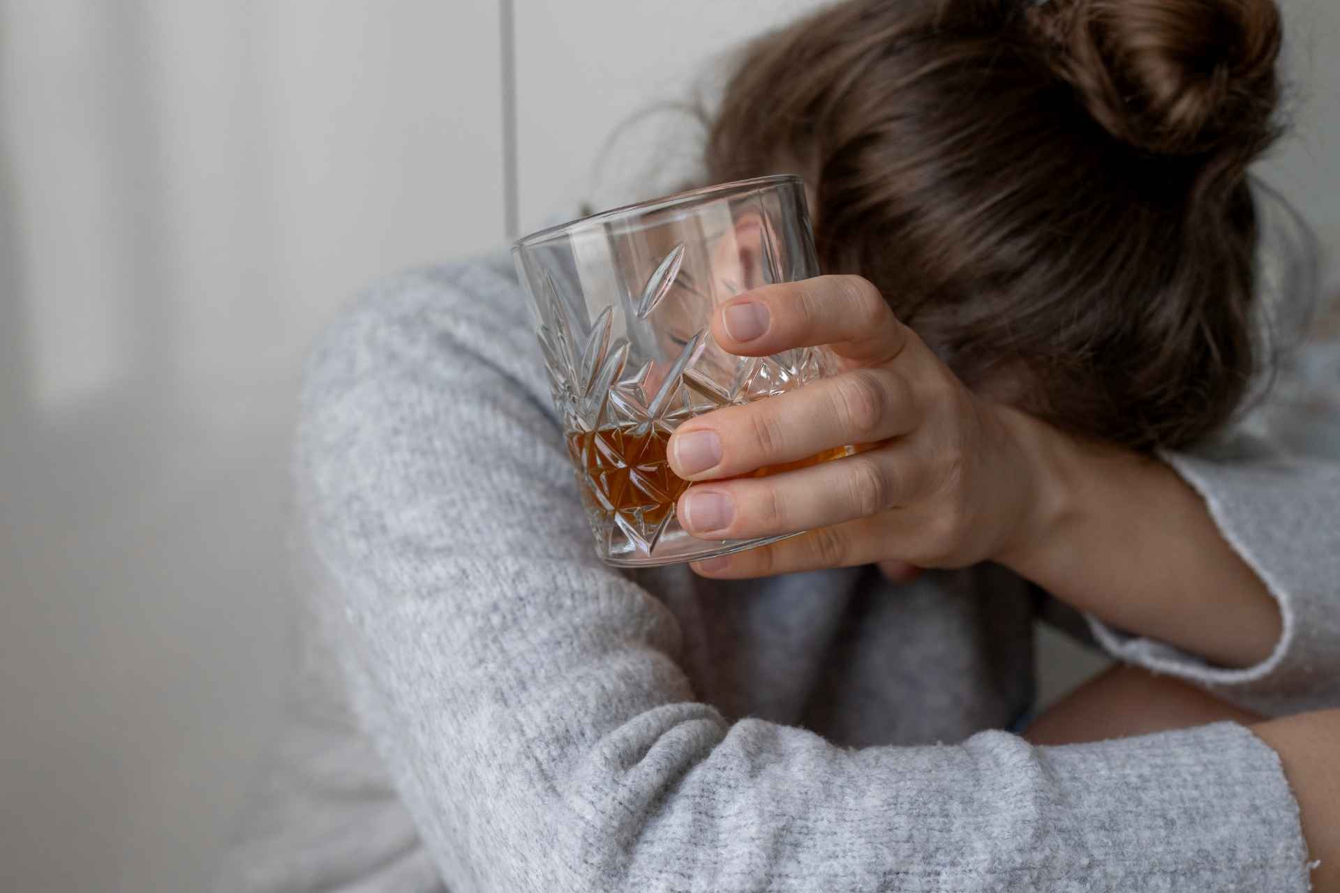 Woman struggling with alcohol use while holding a glass of liquor